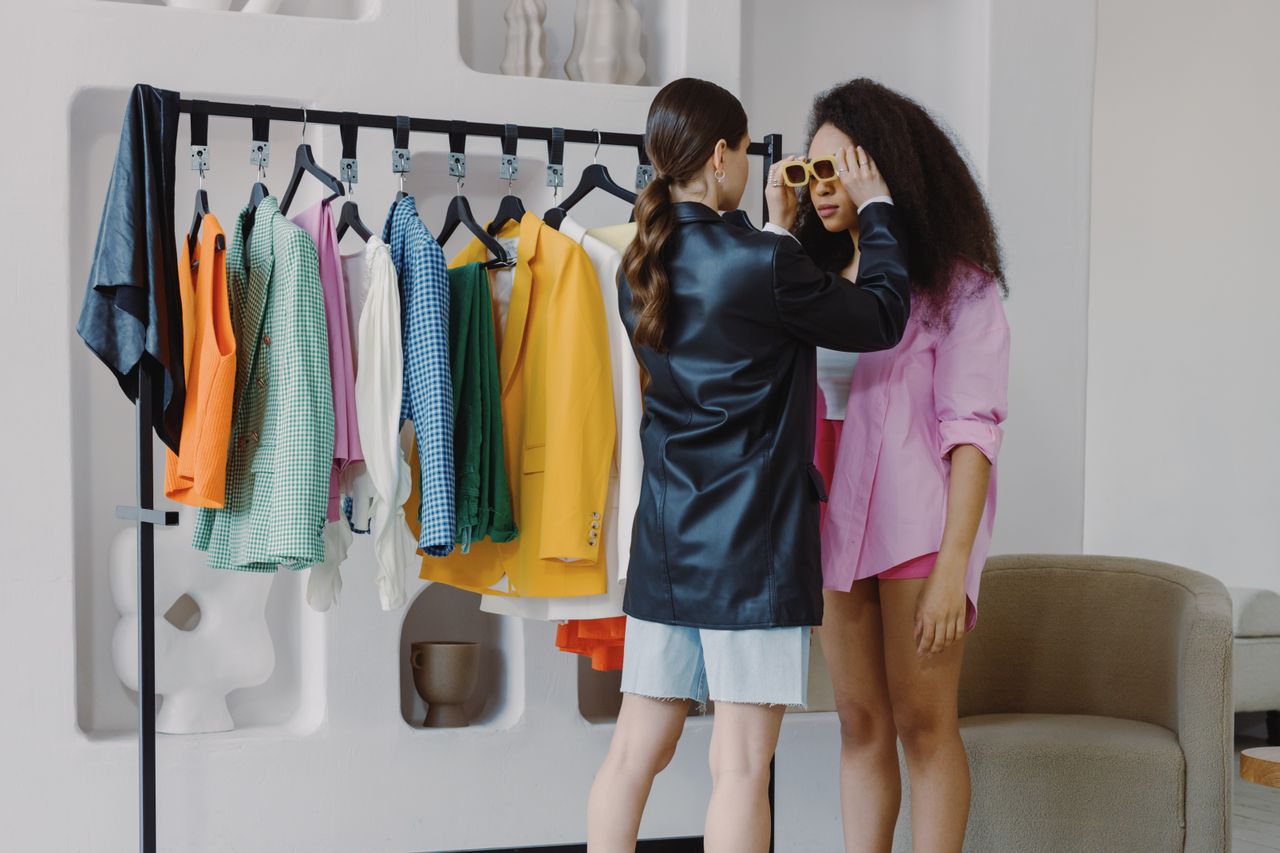 hero Fashion stylist assists client in a vibrant wardrobe fitting, ensuring perfect accessory choices.